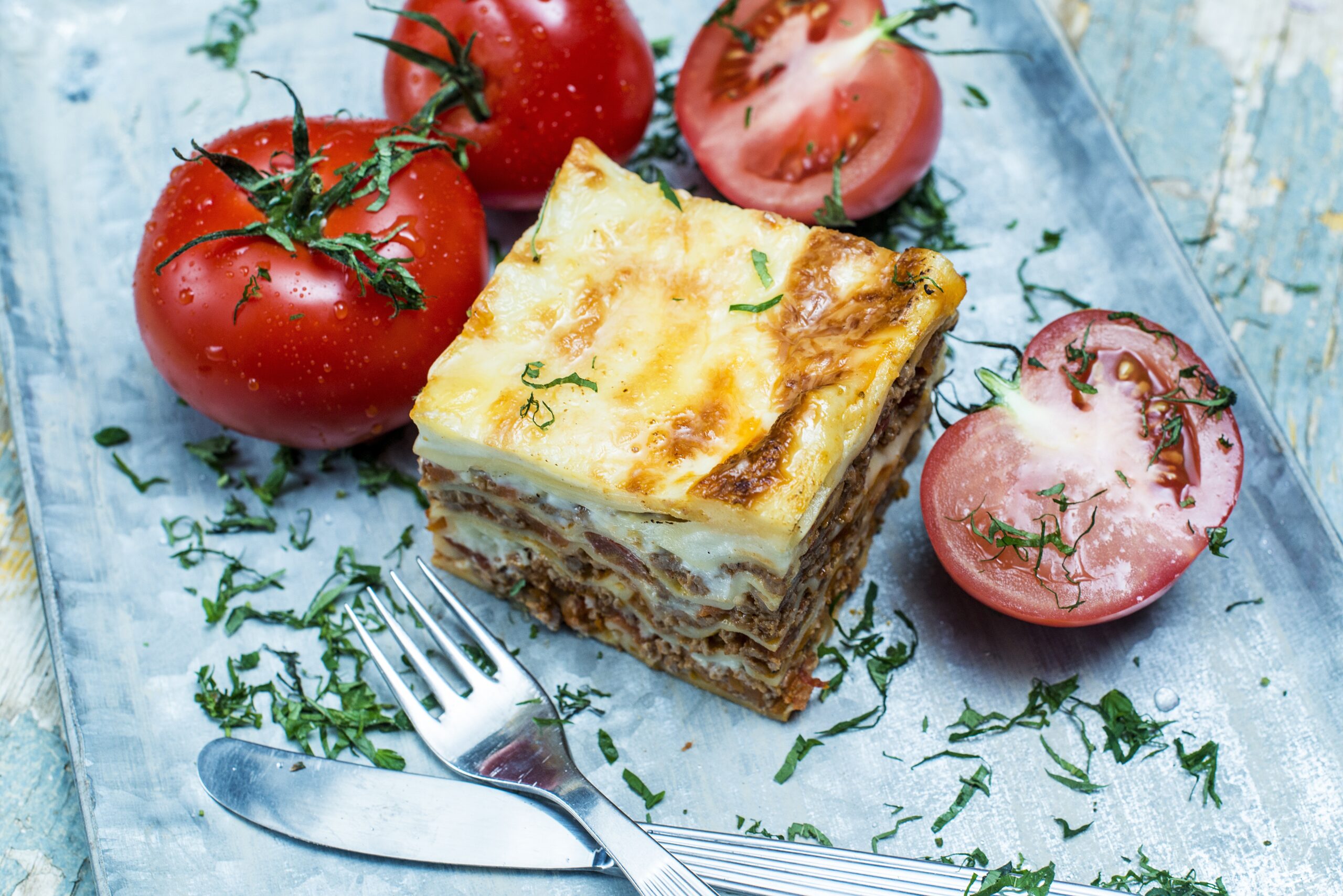 A high angle shot of lasagna and fresh tomatoes on a plate - perfect for a food blog